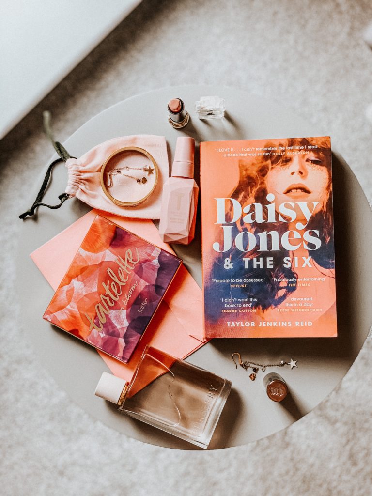 Daisy Jones & The Six book on a grey table with various pink props.